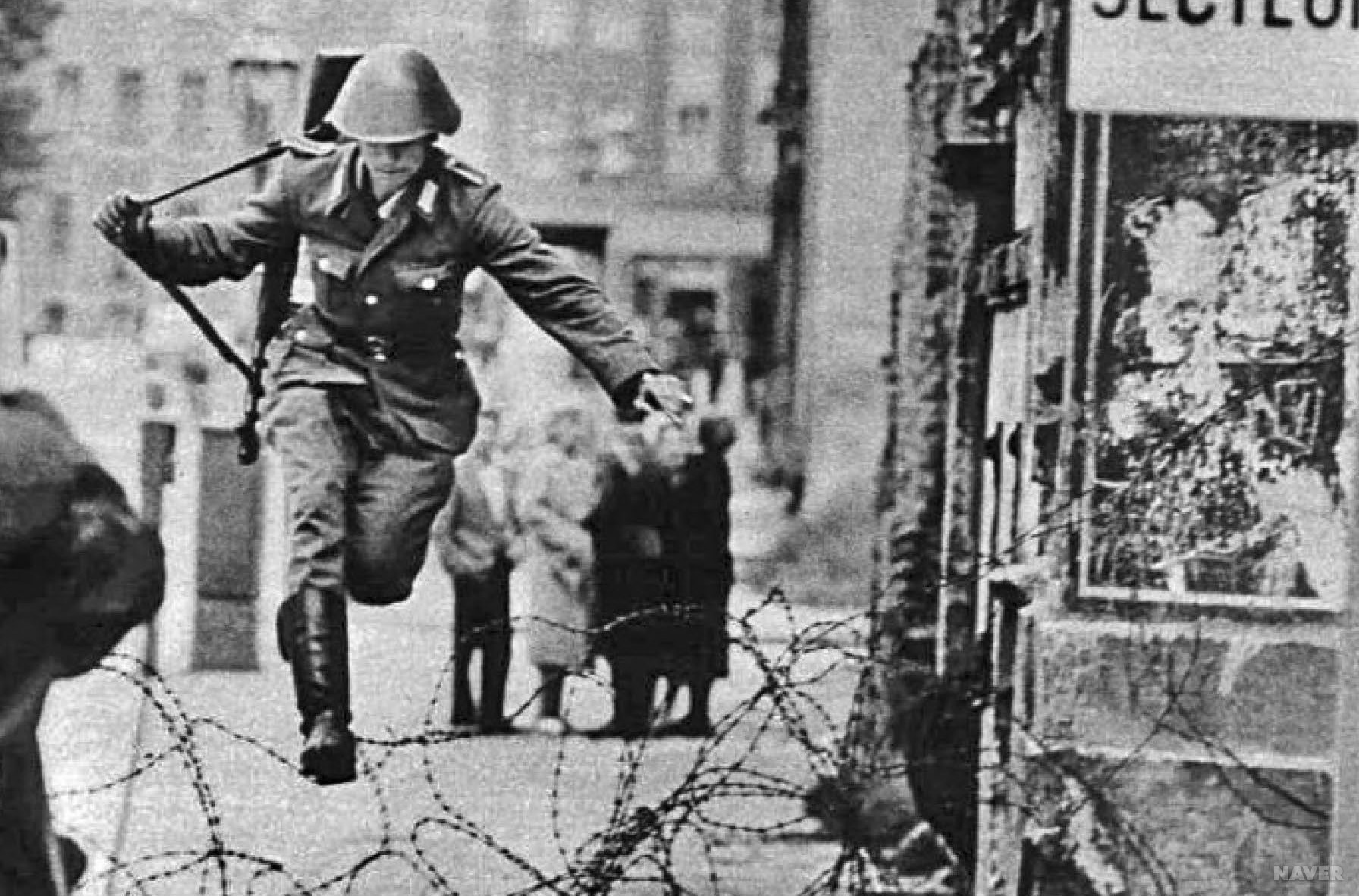 베를린을 동서로 나누는 철조망이 설치된 지 얼마 지나지 않은 1961년 동독 장교 콘라트 슈만(Conrad Schumann)이 서베를린으로 탈출하고 있다.